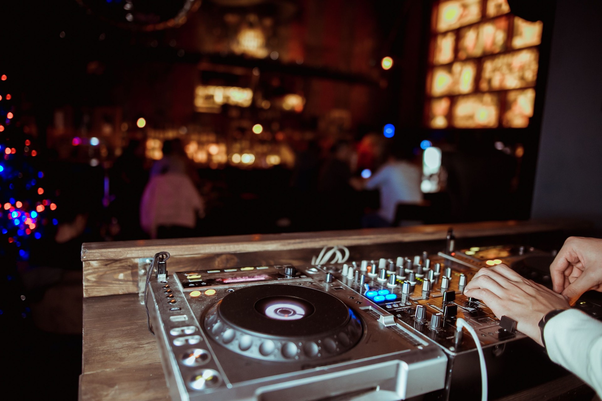 DJ spielt Live-Set und Mixing-Musik auf Der Drehtischkonsole auf der Bühne im Nachtclub. Disc Jokey Hands auf einer Soundmixer-Station bei Clubparty. DJ-Mixer-Controller-Panel zum Abspielen von Musik und Party.
